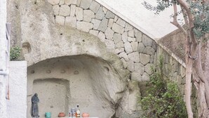 A stone archway leading to a patio with a table, chairs, and a rustic barrel. - Appartamento in pietra di tufo verde Ischitana, Forio (Forio)