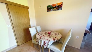 A dining area with a round table, four chairs, and a floral tablecloth. - Apartment Combaj 3 (Jadranovo)