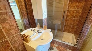 A bathroom with a white sink, a mirror, and a glass shower enclosure. - Apartment Combaj 3 (Jadranovo)