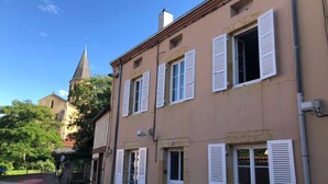 Ein Gebäude mit mehreren Fenstern und Fensterläden, einer sichtbaren Tür und einer Straße davor.