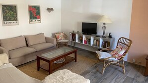 Ein Wohnzimmer mit einer Couch, einem Couchtisch, einem Fernseher und einem Bücherregal.