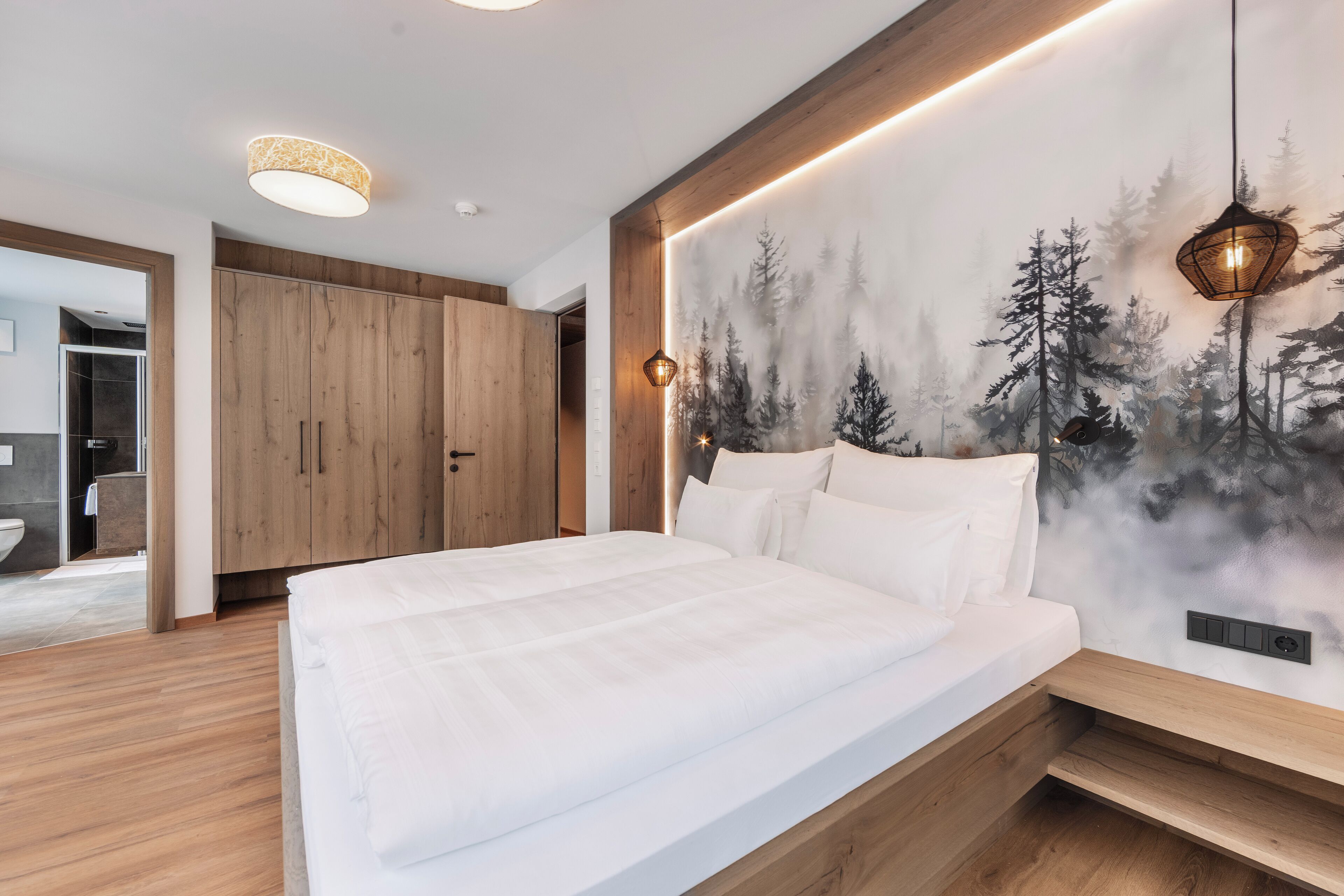 Ein modernes Schlafzimmer mit einem großen Bett, einem Holzschrank und einem Wandbild mit Waldmotiv.