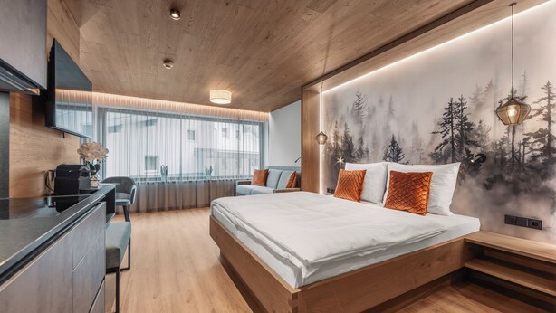 Ein modernes Schlafzimmer mit einem großen Bett, einem Schreibtisch und einem an der Wand montierten Fernseher.