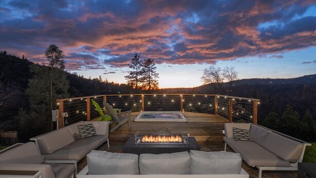 An outdoor deck with a fire feature, seating, and string lights.