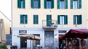 A building with multiple windows and a balcony. There is a sign with the text "ECZZ" on the ground floor. - Easylife - Charm & Comfort in Navigli Area (Milano)
