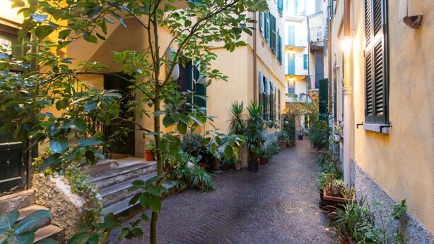 A narrow cobblestone alley flanked by buildings with balconies and potted plants. - Easylife - Charm & Comfort in Navigli Area (Milano)