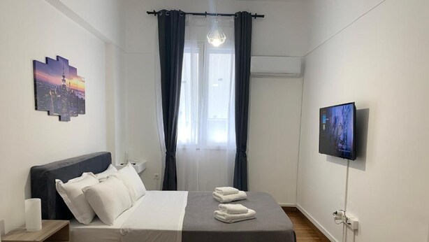 A modern bedroom with a bed, a TV, and a cityscape painting. - Athenian Stay Kolonaki Apartment (Athens)