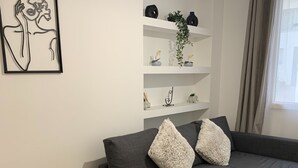 A modern living room with a grey sectional sofa, a small table, and a white shelving unit with decorative items. - Athenian Stay Kolonaki Apartment (Athens)
