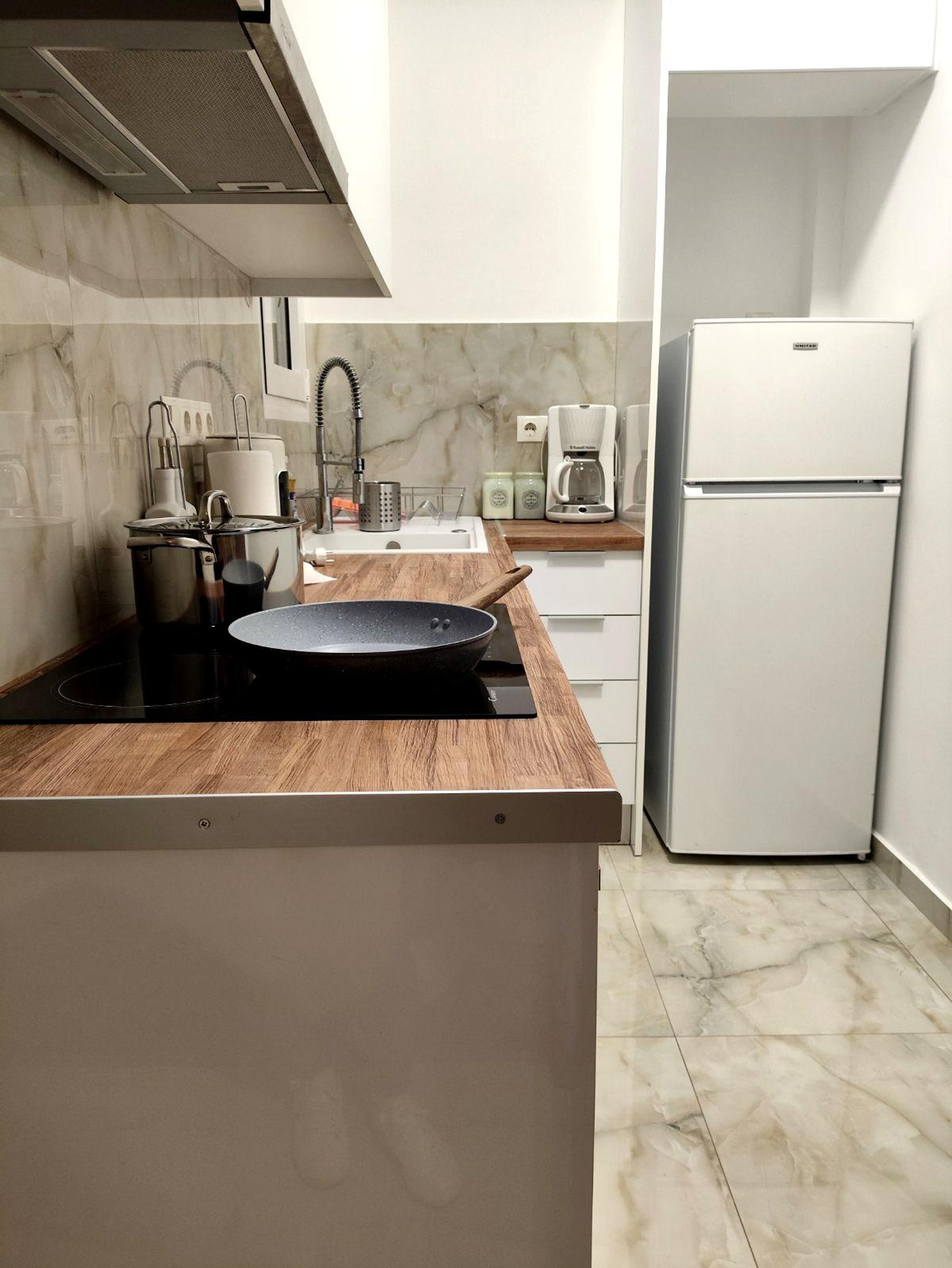 A compact kitchen with a wooden countertop, a built-in stove, a sink, and a white refrigerator.