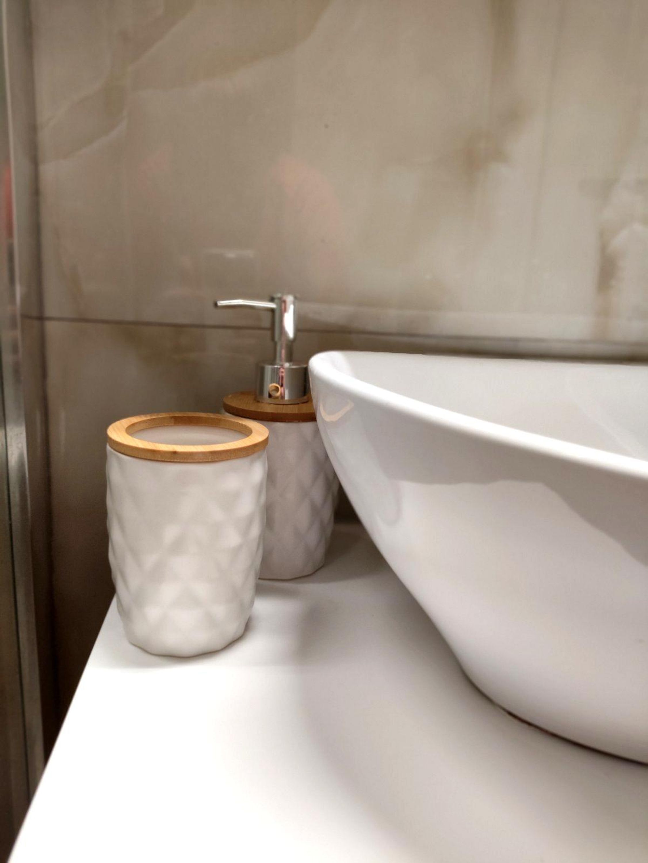 A bathroom with a white sink and two ceramic containers with wooden lids.