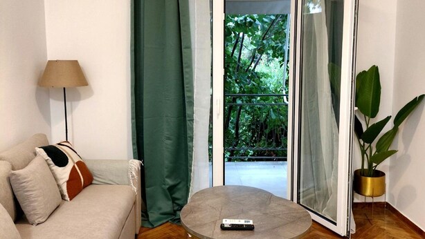 A modern living room with a sofa, a round coffee table, and a potted plant. - Athenian Stay Chara s Apartment (Chalandri)