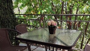 A glass-top table with wicker chairs, a potted plant, and a metal railing. - Athenian Stay Chara s Apartment (Chalandri)