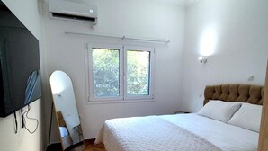A bedroom with a bed, a window, a ceiling fan, and a wall-mounted air conditioner. - Athenian Stay Chara s Apartment (Chalandri)