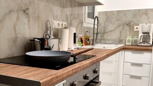 A modern kitchen with a built-in stove, oven, and microwave. There is a wooden countertop, a sink, and a coffee maker. - Athenian Stay Chara s Apartment (Chalandri)
