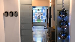 Um saguão de hotel com piso de pedra polida, um tapete de boas-vindas e um ramo de Natal.