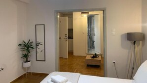 Una habitación de hotel moderna con una cama, una planta en maceta, un espejo y una lámpara en el techo.