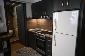 Een moderne keuken met donkere kastjes, een RVS-fornuis, een witte koelkast en een houten aanrecht.