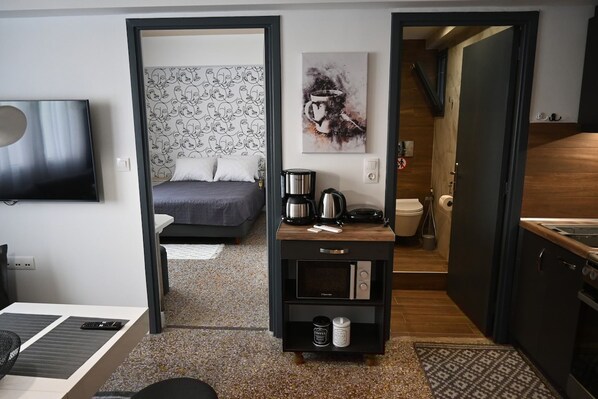 A compact hotel room with a bed, a coffee station, a TV, and a kitchenette. - Athenian Stay 303 Apartment (Athens)