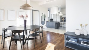 Een moderne keuken met een centraal eiland, een eetgedeelte met een ronde tafel en stoelen, en een woonkamer met een bank en salontafel.
