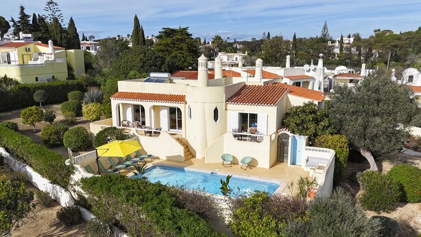Una villa de estilo mediterráneo con piscina, varios balcones y exuberante vegetación.
