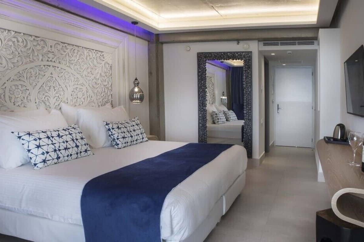 Een hotelkamer met een groot bed, een bureau, een spiegel en een televisie.