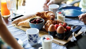 A breakfast setting with croissants, strawberries, cherries, and a glass of orange juice on a table. - Romantic luxury apartment  great garden with fire table 5 minutes to the forest. (Wilbertoord)
