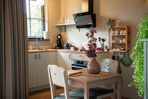 Ett modernt kök med ett matbord, stolar, en vas med blommor och en tv som är monterad ovanför köksbänken.