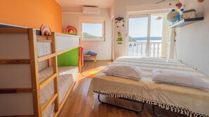A bedroom with bunk beds, a window with a view, and a balcony with a railing. - Apartment Ahel (Jadranovo)
