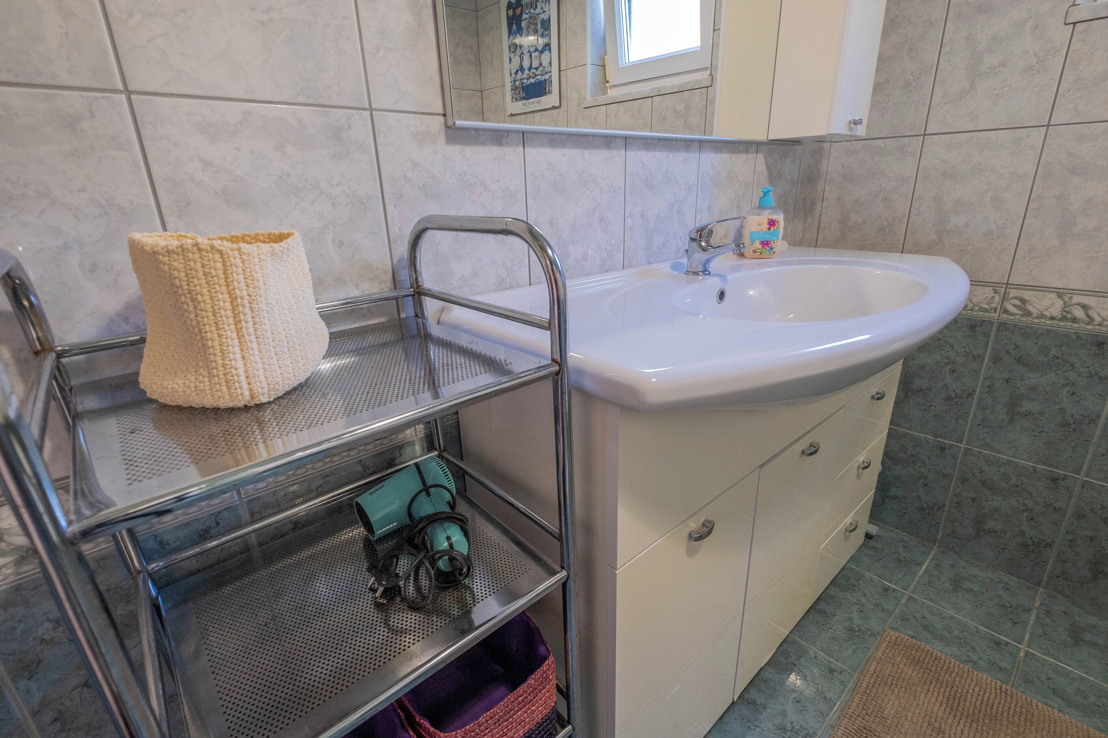 Une salle de bain avec un lavabo, un porte-serviettes, un miroir et un sol carrelé.