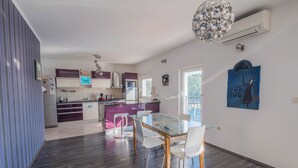 A modern kitchen with a central island, white chairs around a glass table, and a decorative ceiling light. - Apartment Ahel (Jadranovo)