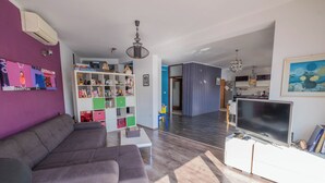 A modern living room with a sectional sofa, a TV, and a bookshelf. - Apartment Ahel (Jadranovo)