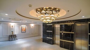 En modern entréhall med ett marmorgolv, en svart marmorhiss och en unik, cirkelformad kristallkrona.