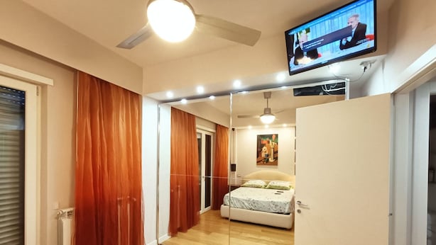 A bedroom with a bed, a television mounted on the wall, and a ceiling fan. - Artemisia Apartment (VITERBO)