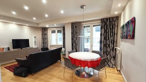 A modern living room with a round table, black sofa, and a TV. - Artemisia Apartment (VITERBO)
