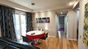 A modern living room with a round dining table, black leather sofa, and a view to the outside. - Artemisia Apartment (VITERBO)