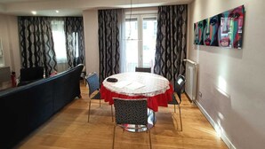 A dining area with a round table covered in a red tablecloth, surrounded by patterned chairs. - Artemisia Apartment (VITERBO)