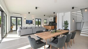 Ein modernes Wohnzimmer mit einem grauen Sofa, einem Holzesstisch mit Stühlen und einer Treppe.