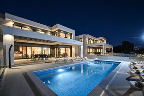 Un hôtel moderne doté d’une piscine, d’un espace extérieur aménagé et d’une façade bien éclairée.