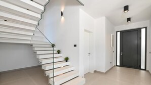 Eine moderne Treppe mit weißen Stufen und Glastrennungen, die zu einer Tür führt.