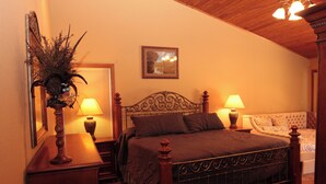 Um quarto com uma cama de madeira, duas mesas de cabeceira com abajures, um vaso decorativo e um quadro na parede.