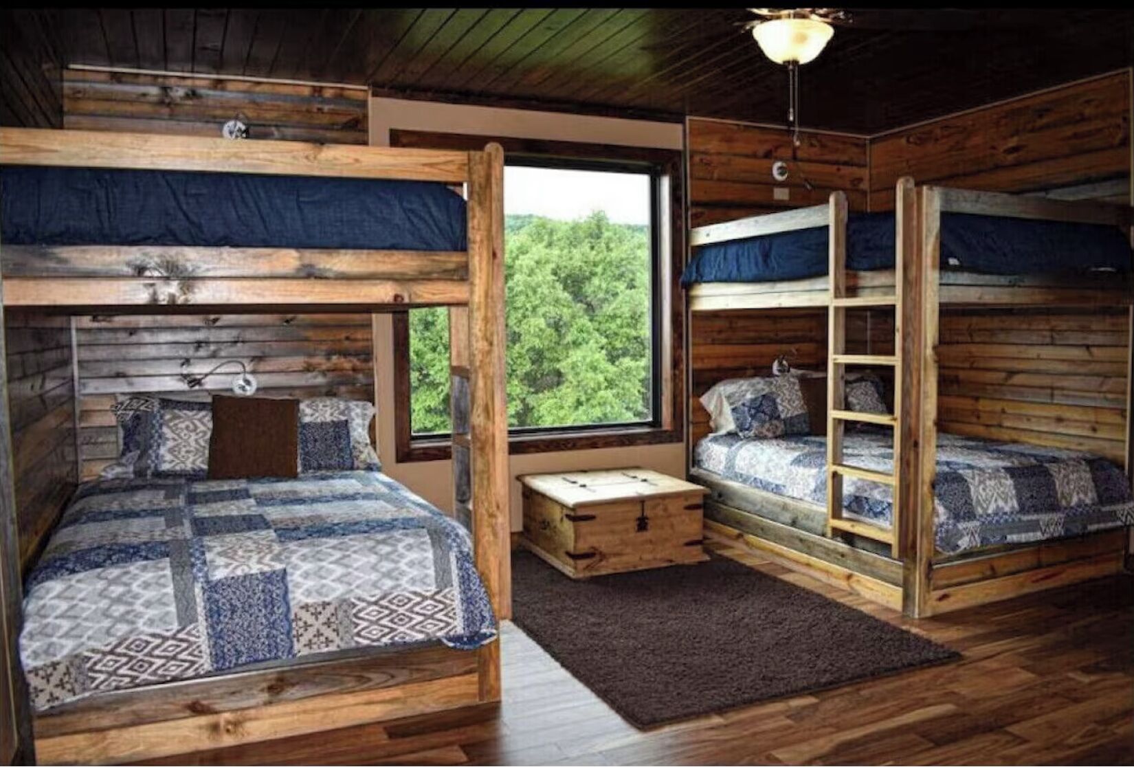 Una cabaña con dos literas, un cofre de madera y una ventana que da a un bosque.