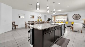 A modern kitchen with a central island, dark cabinetry, and pendant lighting. - The Fantasy 8BR Villa at Windsor Westside/Pool/Spa (Kissimmee)