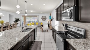 A modern kitchen with granite countertops, stainless steel appliances, and a central island. - The Fantasy 8BR Villa at Windsor Westside/Pool/Spa (Kissimmee)
