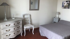 A bedroom with a bed, dresser, chair, lamp, and mirror.