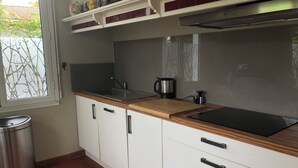 A modern kitchen with white cabinets, a wooden countertop, a stainless steel sink, and a window with a view of greenery outside.