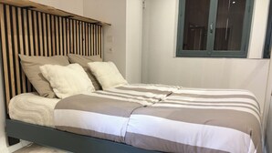 Een bed met een houten hoofdbord, een gestreept dekbed en twee kussens.
