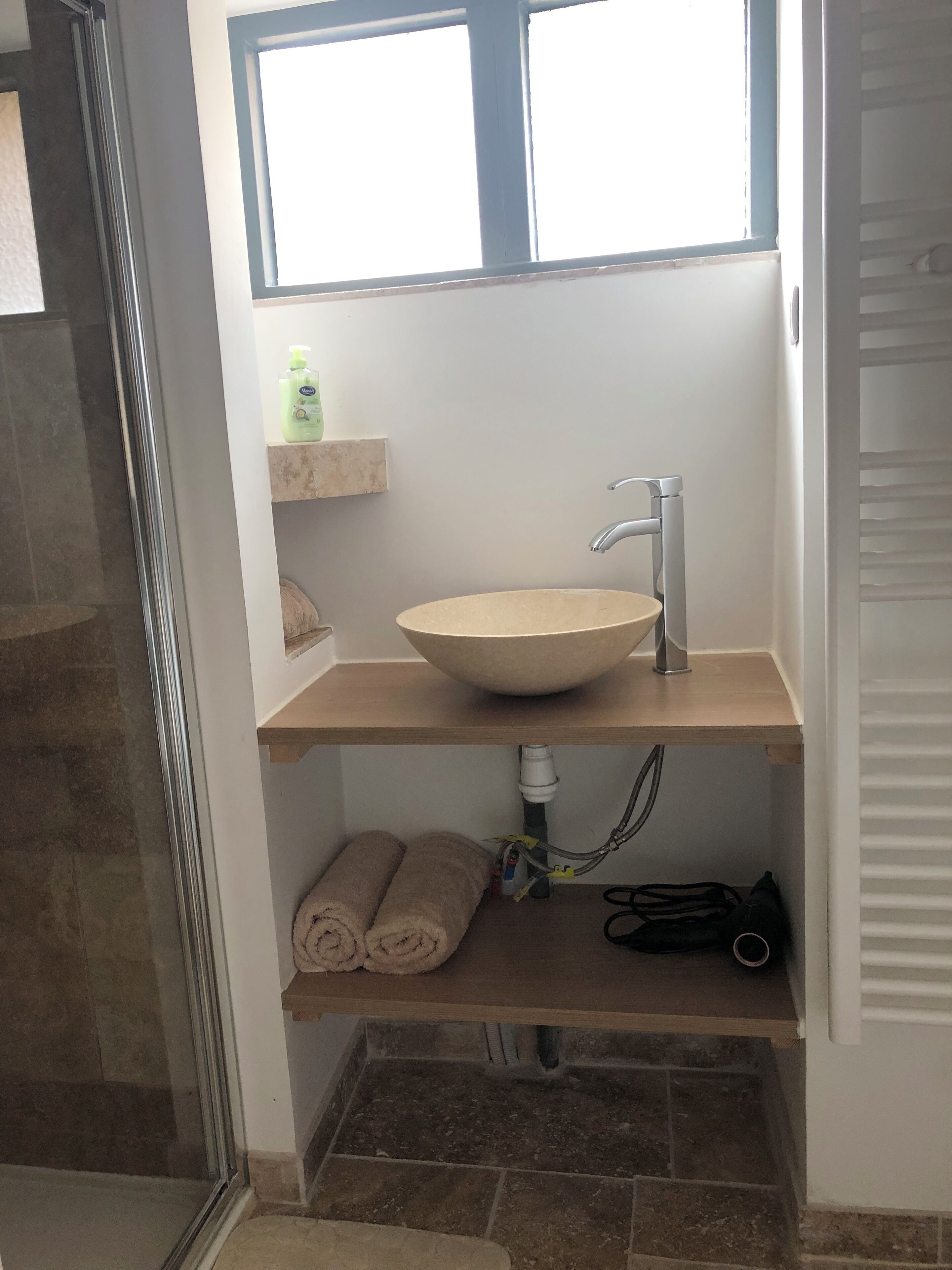Ein Badezimmer mit einem großen Waschbecken, einem Handtuchhalter und einer Duschkabine.