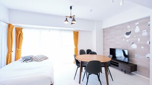 A modern hotel room with a bed, a dining table with chairs, a TV, and a wall with decorative stickers. - Creare Togoshi Ginza by Tranova (Tokyo)
