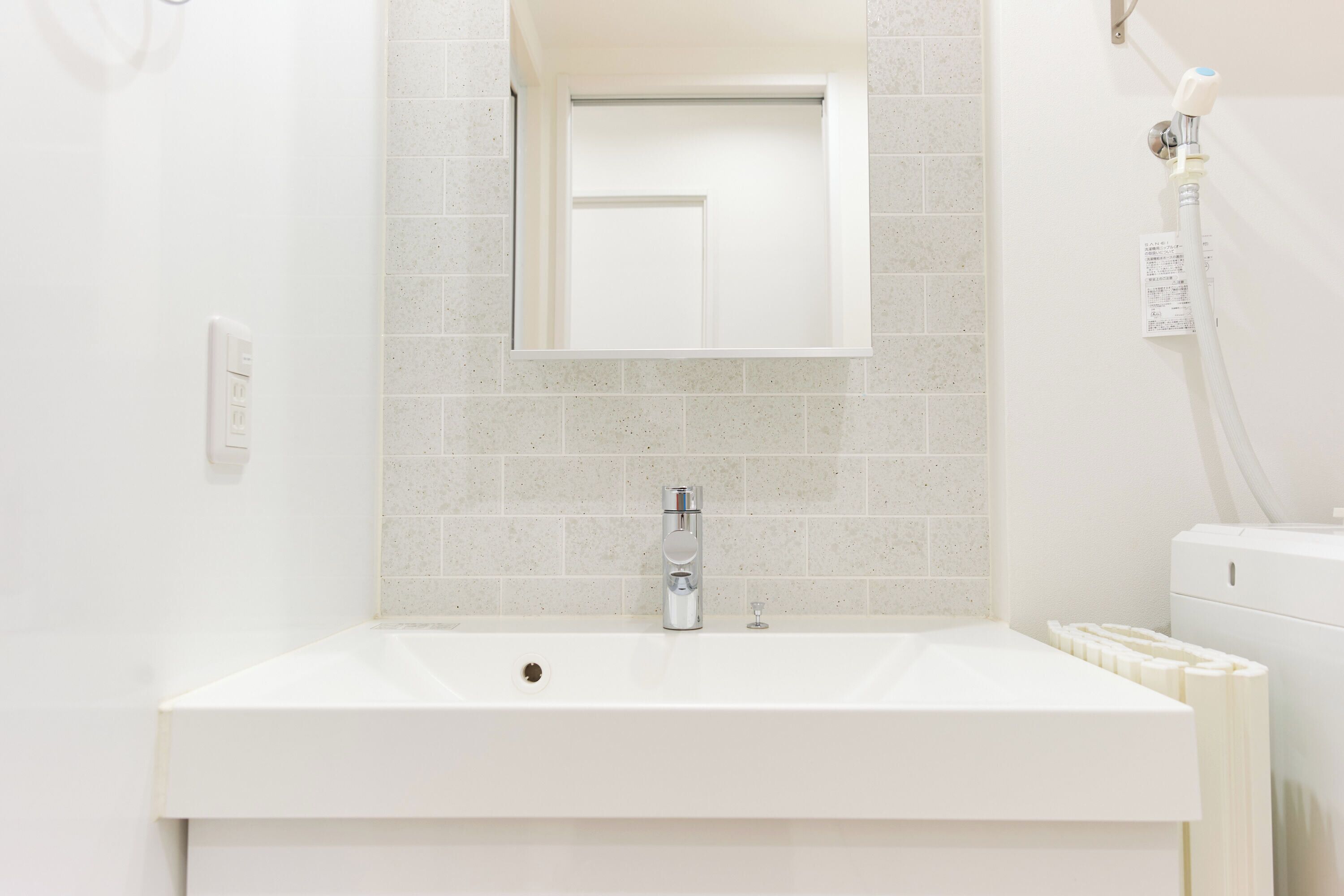 Une salle de bain avec un lavabo blanc, un miroir et un porte-serviettes.