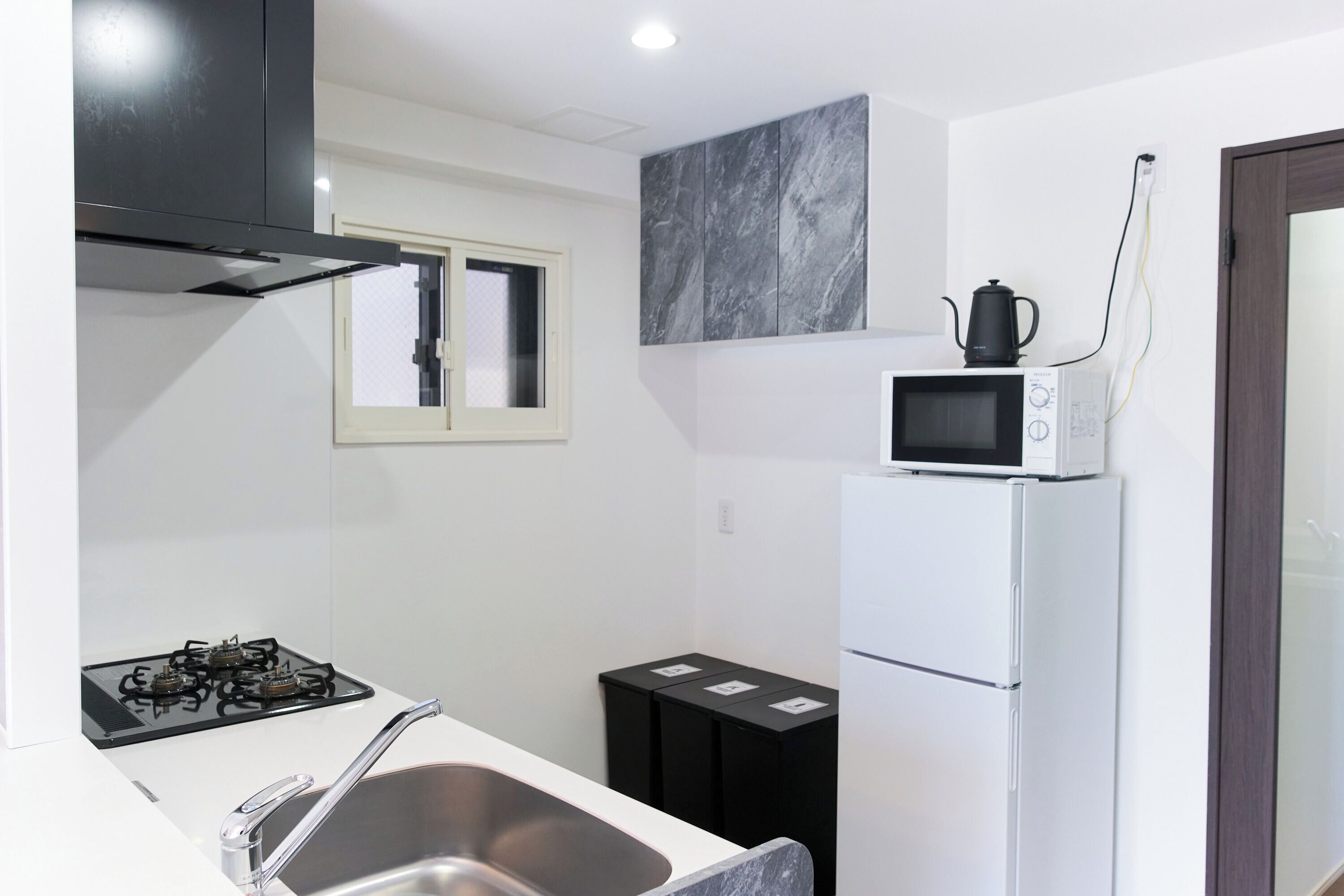A modern kitchen with a gas stove, stainless steel sink, microwave, and a refrigerator.